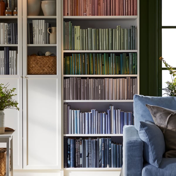 A man sits on one of two light-beige SÖDERHAMN one-seat sections in a living area with a wall of book-filled BILLY bookcases.
