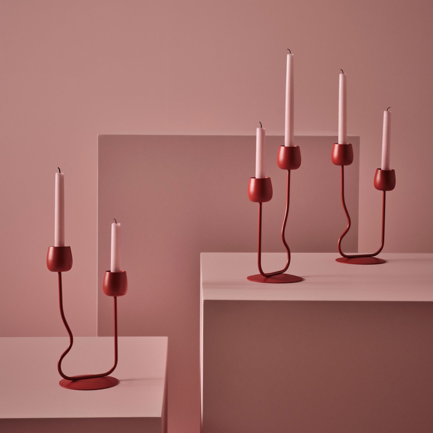 A pink background with new red organic SILVERPÄRON candle holders.