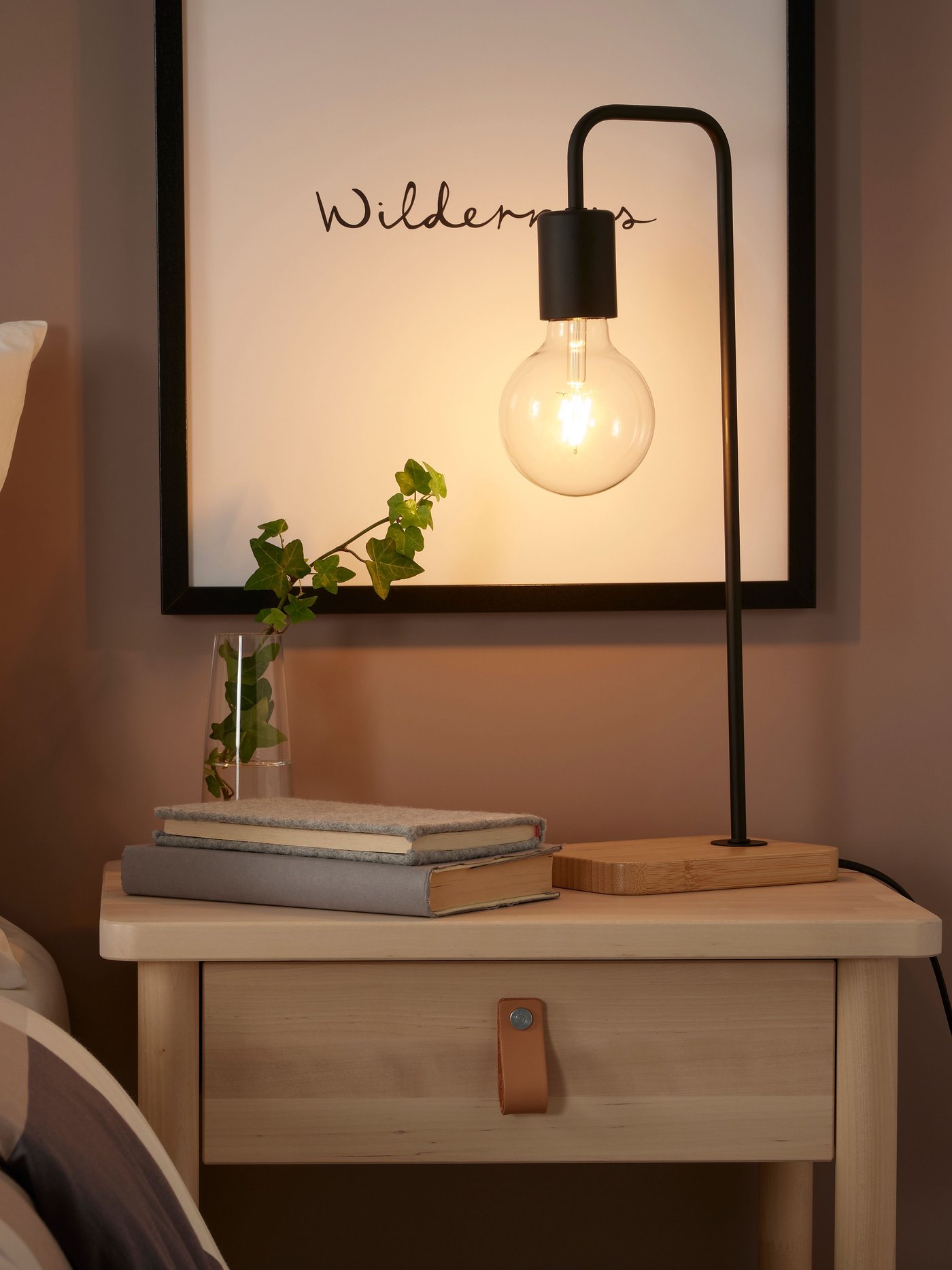 A black/bamboo TVÄRHAND table lamp in the bedroom