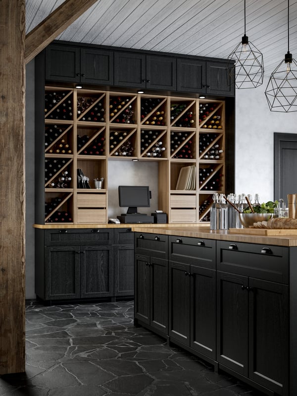 A kitchen island with black stained doors, wine shelves put together to create a statement wall, a cash register.