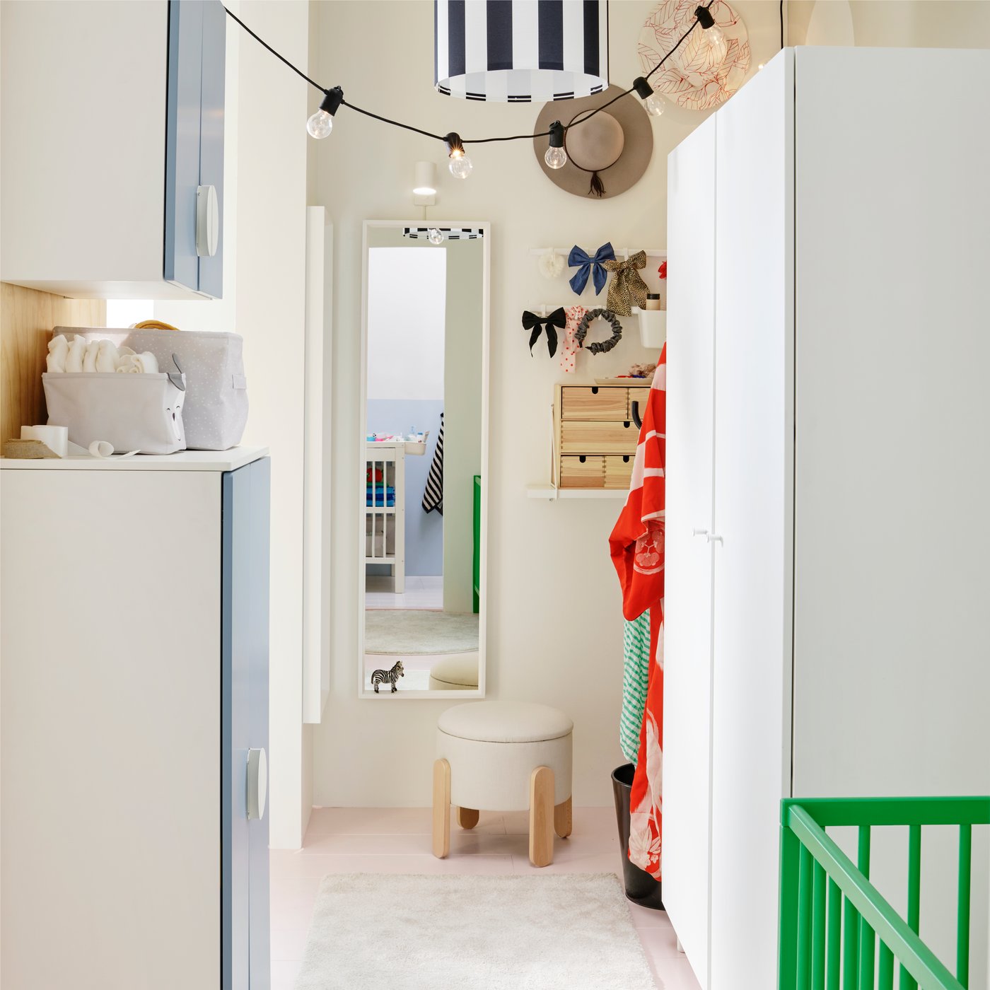 Una zona spogliatoio con un armadio bianco PLATSA su un lato e uno specchio NISSEDAL appeso alla parete di fondo con uno sgabello davanti.