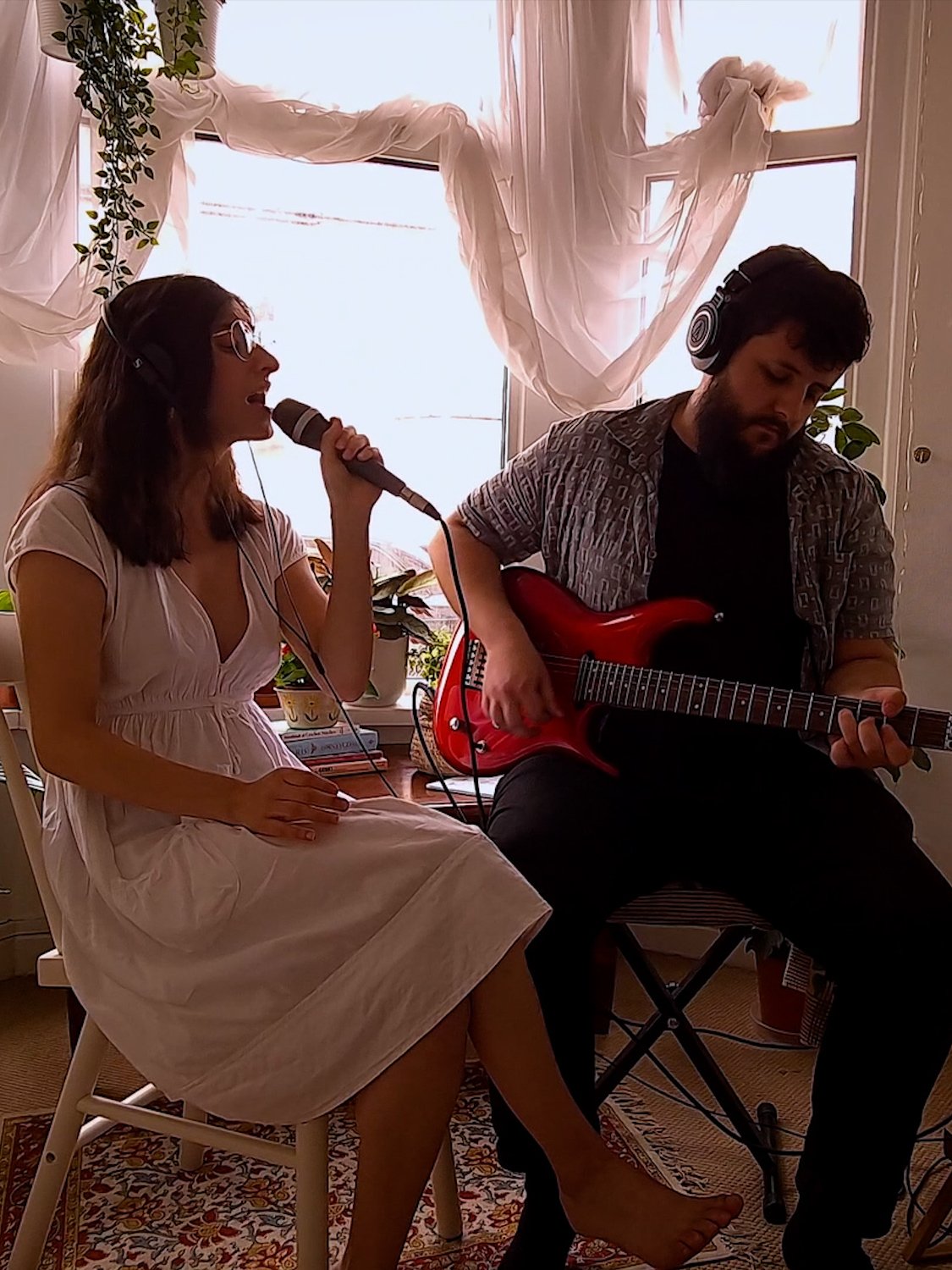 Žena peva s muškarcem koji svira gitaru.