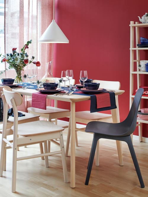 A wooden LISABO table set with dinnerware and four wooden chairs.