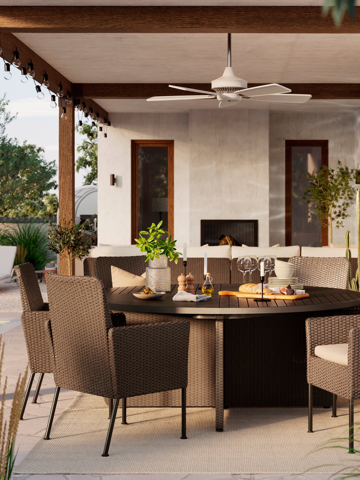 Ett stort runt svart utebord med matchande stolar i konstrotting på terass under tak. 