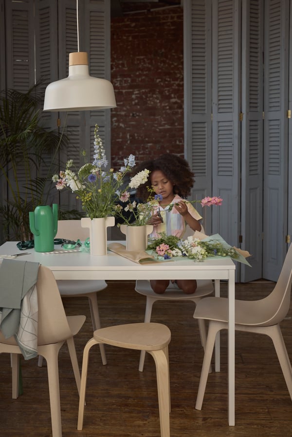 Un enfant se tient près d’une table à manger et de chaises.