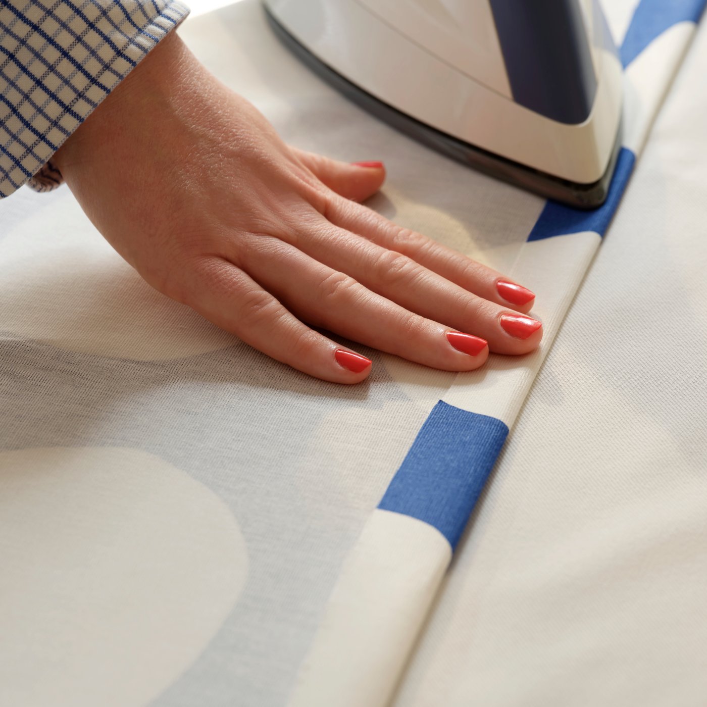 Person som stryker fållen på ett syg som ska sys till gardiner.