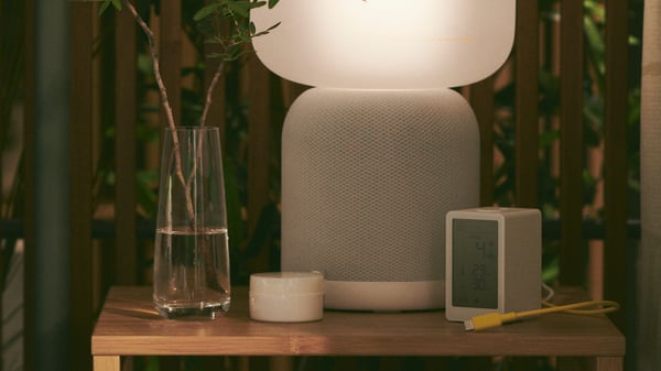 SYMFONISK lamp with WiFi speaker on a table alongside various ornaments