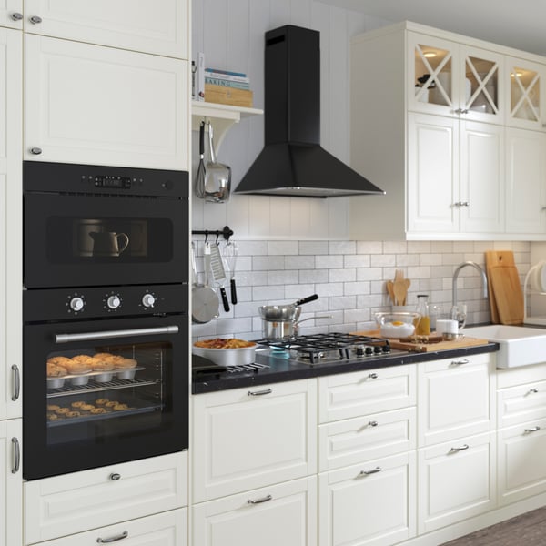 Cuisine blanche moderne avec four encastré, plaque de cuisson et hotte. Aménagement pratique associé à des appareils économes en énergie.