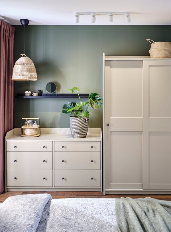 A bedroom with a white HAUGA six-drawer chest of drawers beside a HAUGA wardrobe with sliding doors.