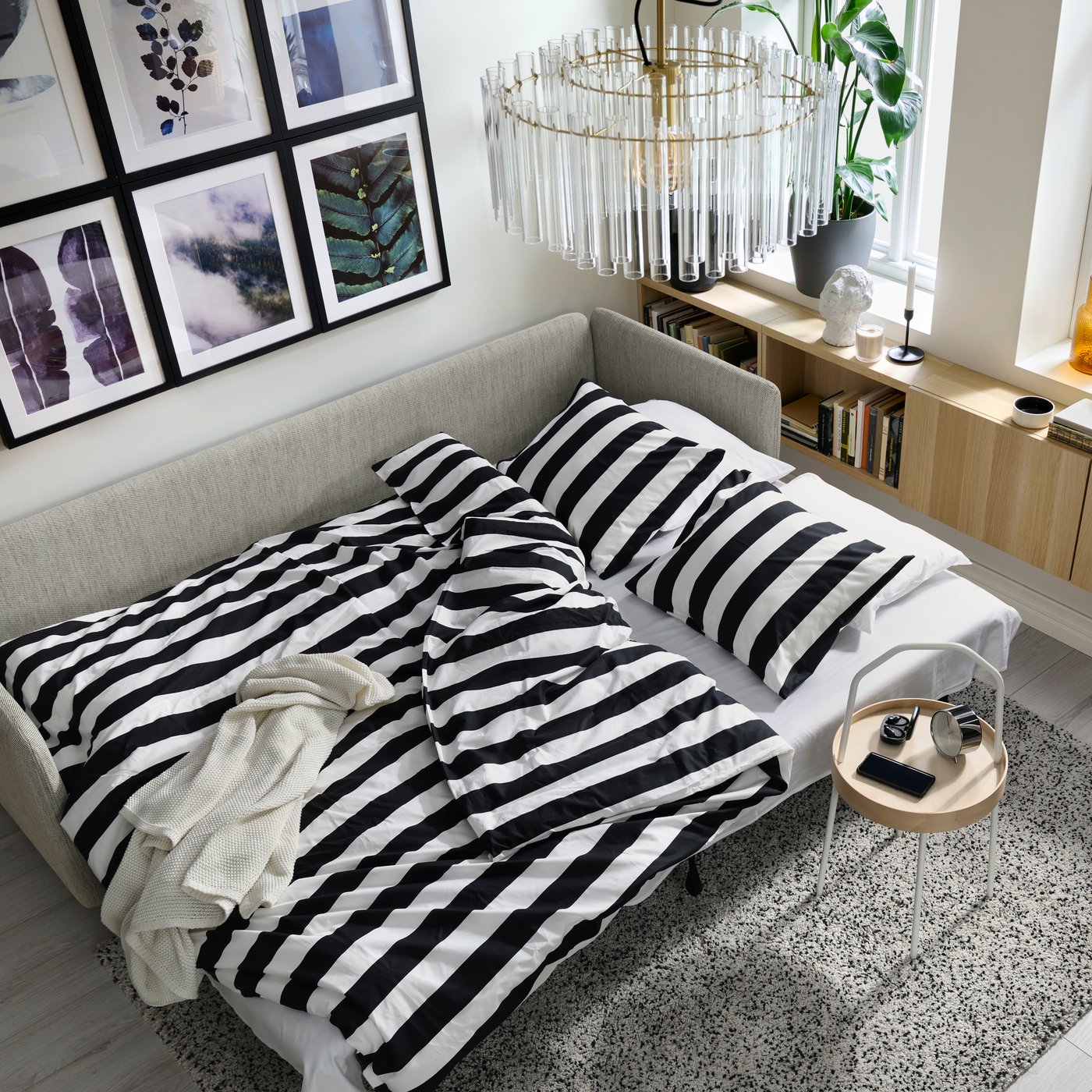 Divano letto SÖDERHAMN da 3 posti in tessuto VIARP beige e marrone, aperto in versione letto con biancheria a righe nere e bianche, ideale per offrire un comodo posto letto extra in soggiorno.