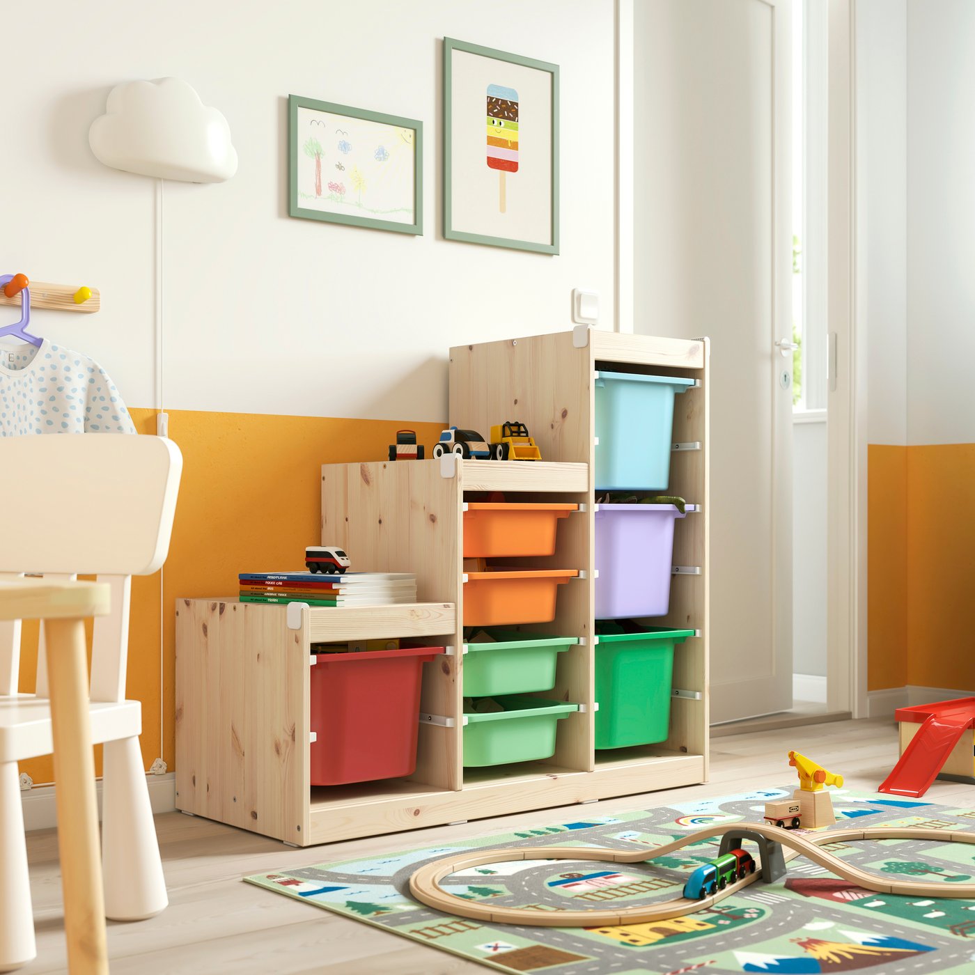 Eine Kombination aus hellweiß gebeiztem Kiefernholz und bunten TROFAST-Aufbewahrungsmöbeln mit Boxen im Kinderzimmer