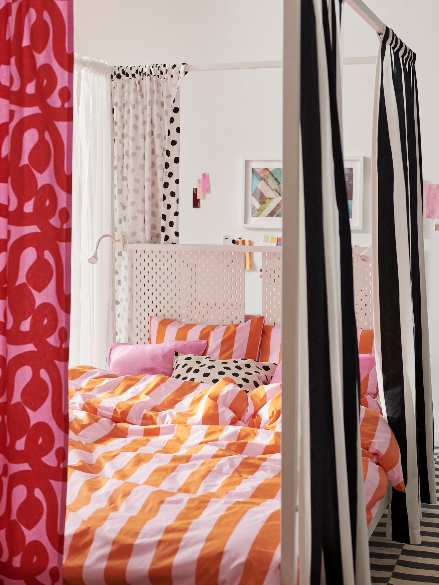 Um ein weißes VITARNA Himmelbettgestell hängt ein Vorhang aus VARGTÖREL und FLUGBLOMSTER Stoffbahnen. Auf dem Bett liegt Bettzeug in SLÅNHÖSTMAL Bettwäsche.