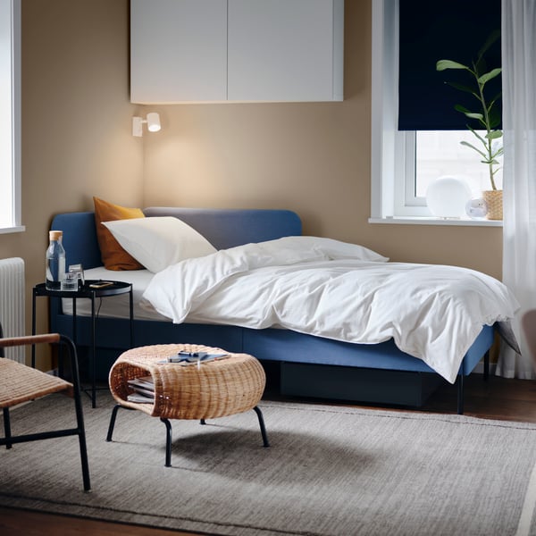 Een opgemaakt slaapbank in een woonkamer met een wit dekbed erop.