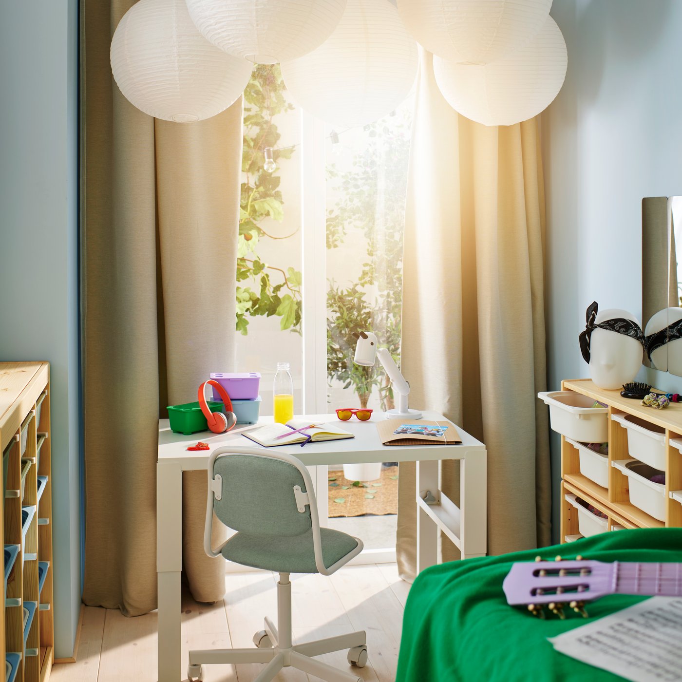 Svetla dečja soba sa zelenim, lila i plavim GLIS kutijama i belim PÅHL radnim stolom na kom je KRUX LED radna lampa.