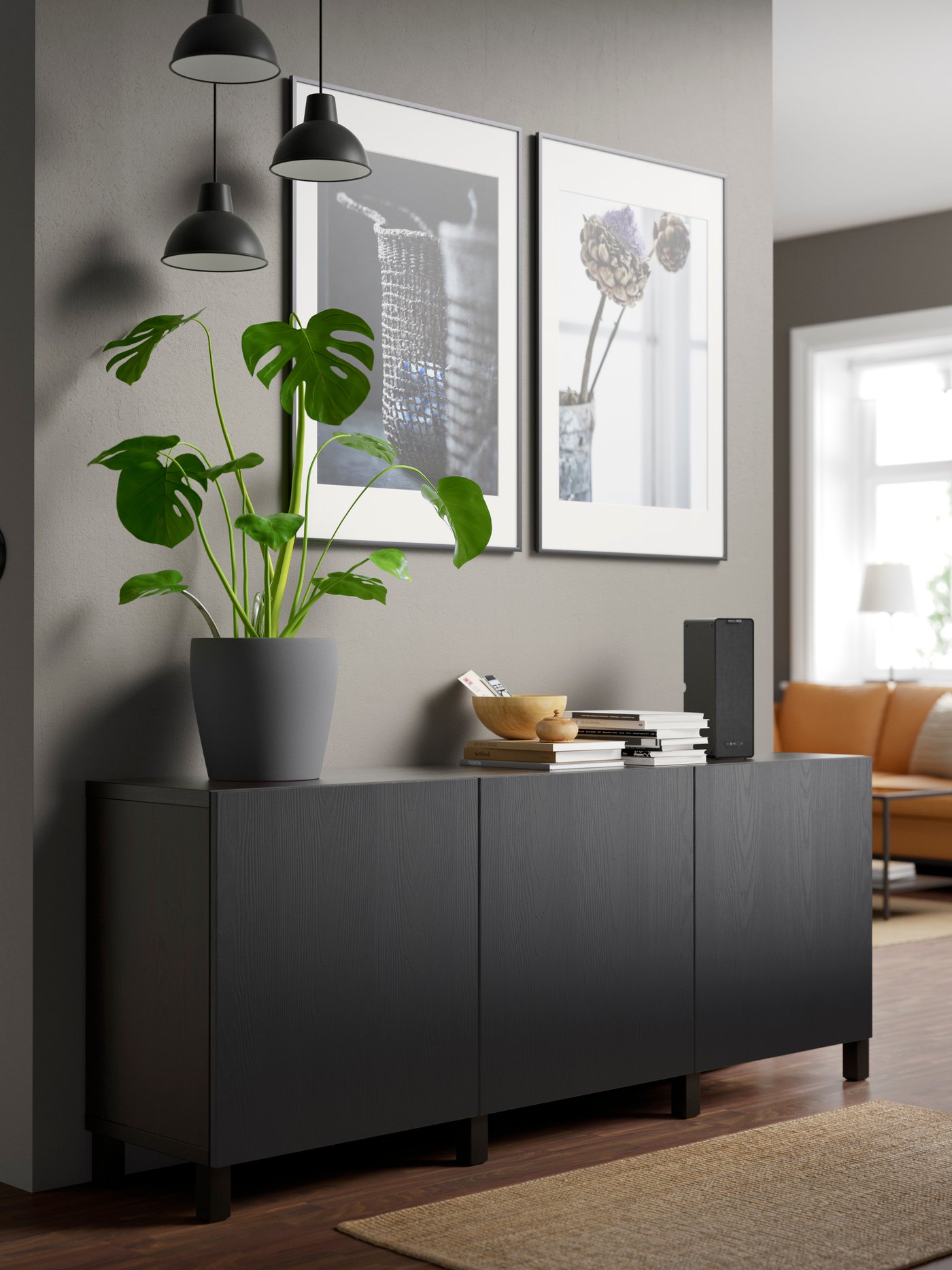 A l'entrée d'une maison, une combinaison de rangement BESTÅ noir-marron/Timmerviken/Stubbarp noir avec portes sur lequel est posé un pot de fleur.