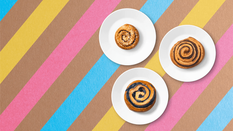 3 unterschiedliche Zimtschnecken auf 3 Tellern auf buntem Untergrund.