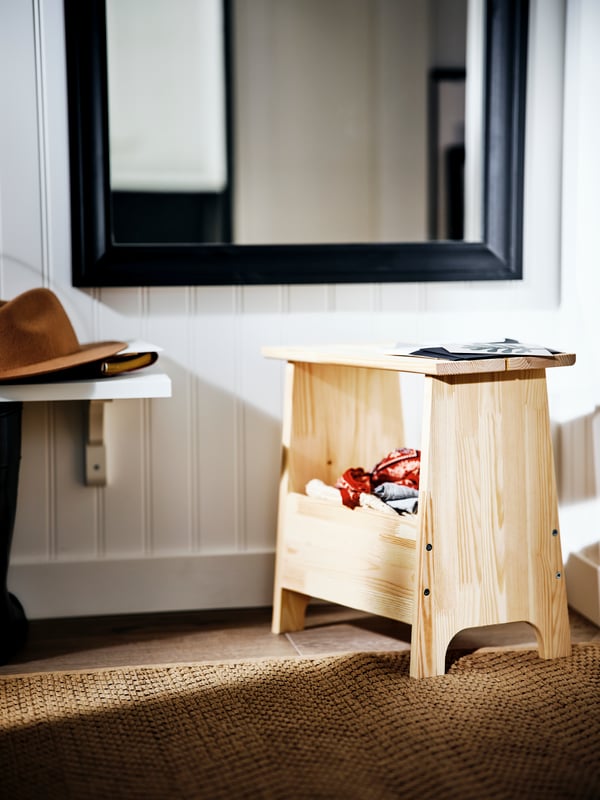 A BILD poster in a black RIBBA frame leaning against a wall on top of a pine PERJOHAN bench with storage.