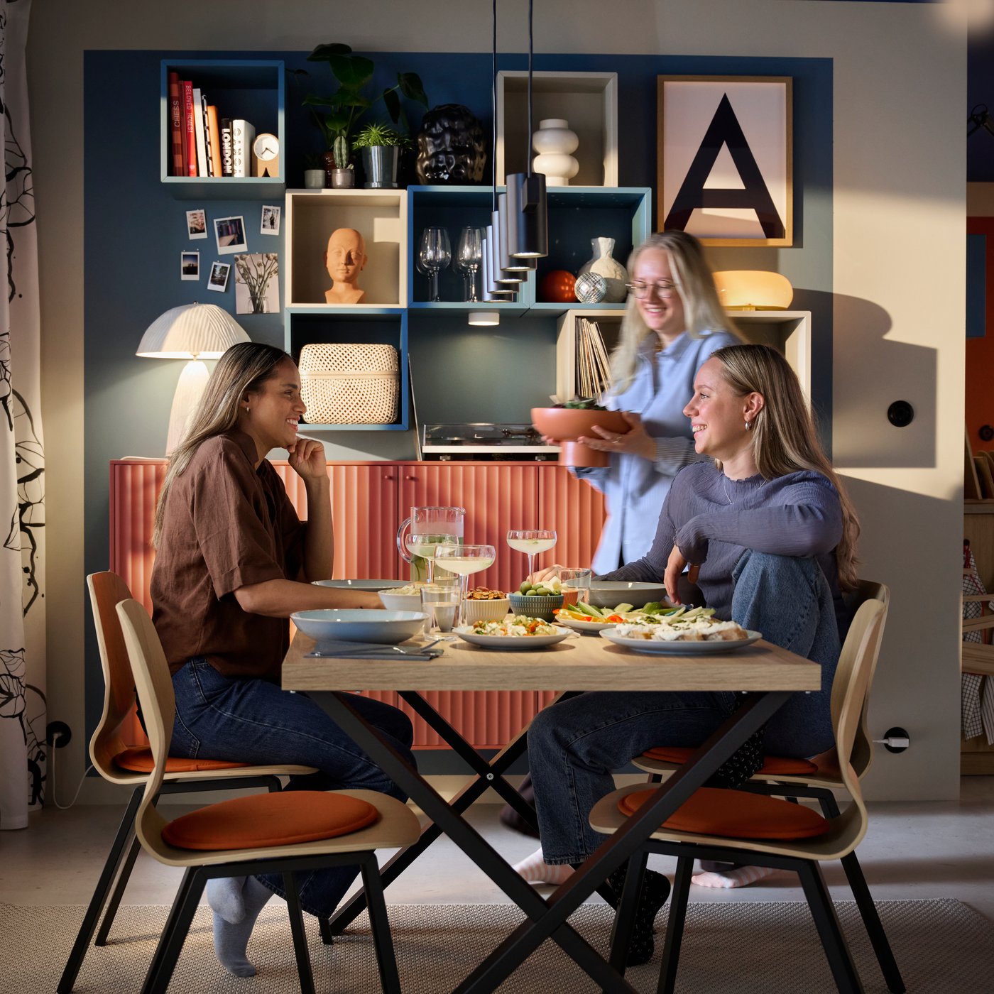 Three people are spending time together in a dining room that has a SKÅLSTA dining table in oak veneer with matching chairs.