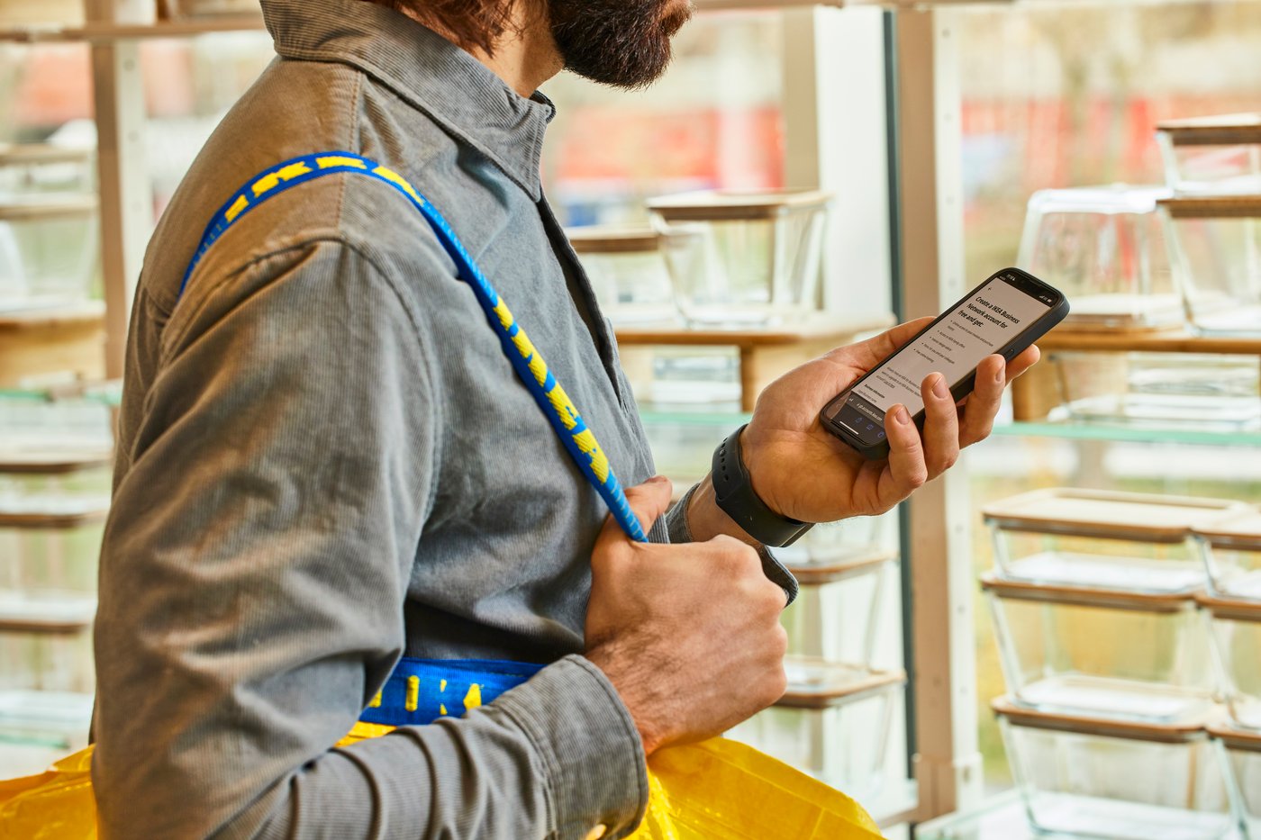 IKEA poltsa bat duen mutil batek telefono mugikorra kontsultatzen du