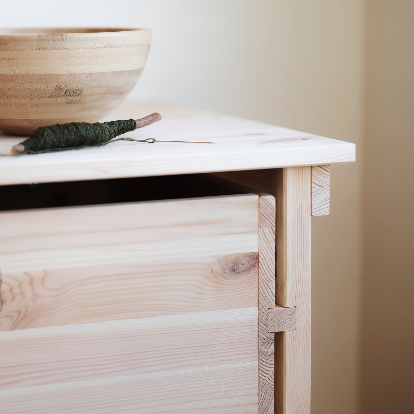 KRONÖREN chest of 2 drawers in pine with decorative bowl on top shown in a light-toned bedroom.