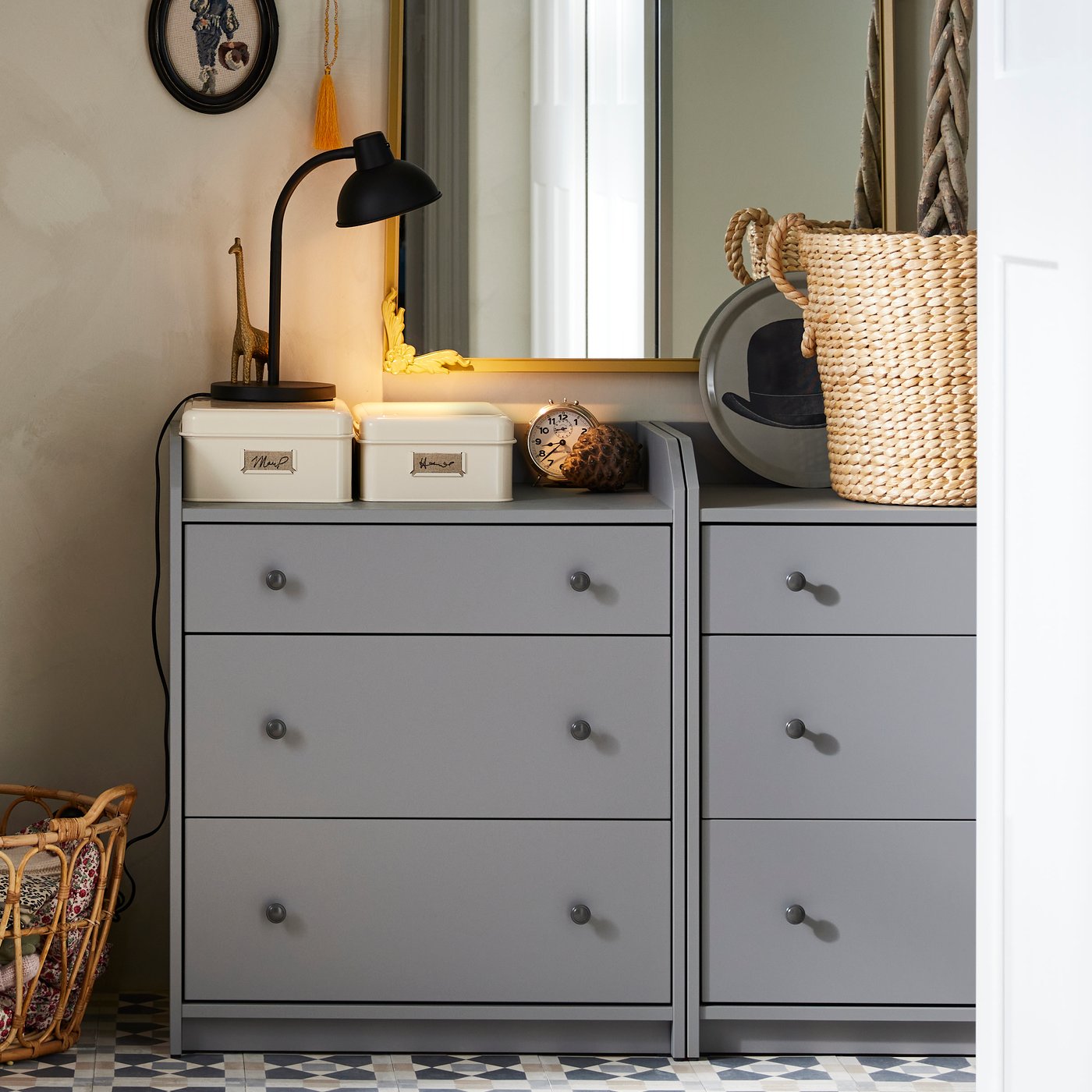 Zrcadlo RÅMEBO zlaté barvy nad komodami v šedé barvě. 