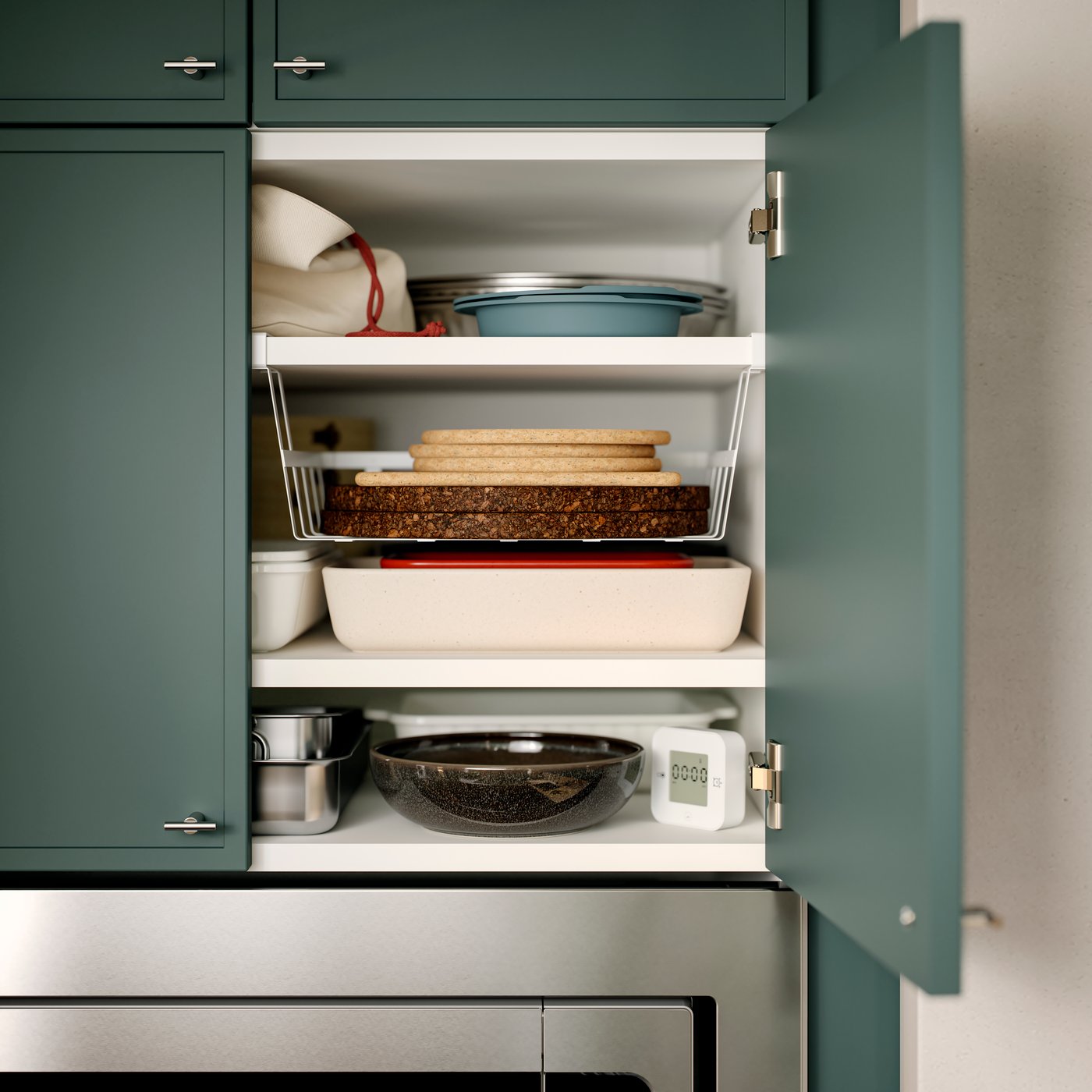A kitchen cabinet has an open door with kitchen items stored on the shelves inside. One shelf has a PÅLYCKE clip-on basket.