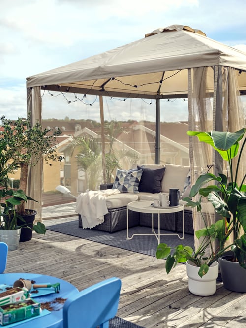A HIMMELSÖ gazebo, SOLLERÖN modular outdoor sofa, and MORUM flatwoven in/out rug form a lounge area on a rooftop.