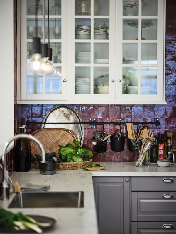 Dapur SEKTION/MAXIMERA dengan permukaan atas kerja EKBACKEN kesan marmar berwarna putih/berlamina dan kabinet dinding berpintu kaca berwarna putih.