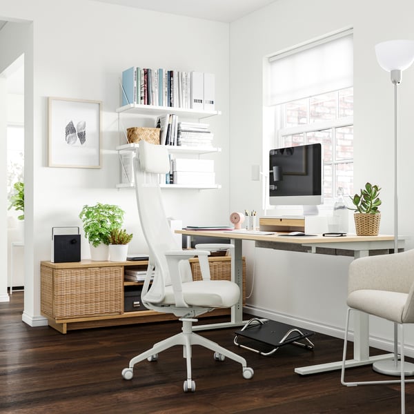 Ein elektrischer Sitz-/Stehschreibtisch MITTZON aus Birkenfurnier/Weiß in einem Homeoffice.