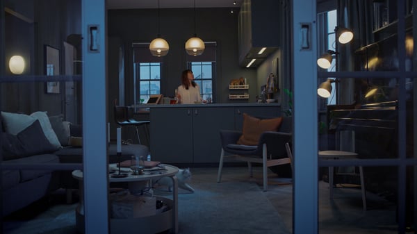 zu sehen ist ein etwas dünkleres Wohnzimmer in dem eine Frau steht die sich gerade die Deckenleuchten ansieht.