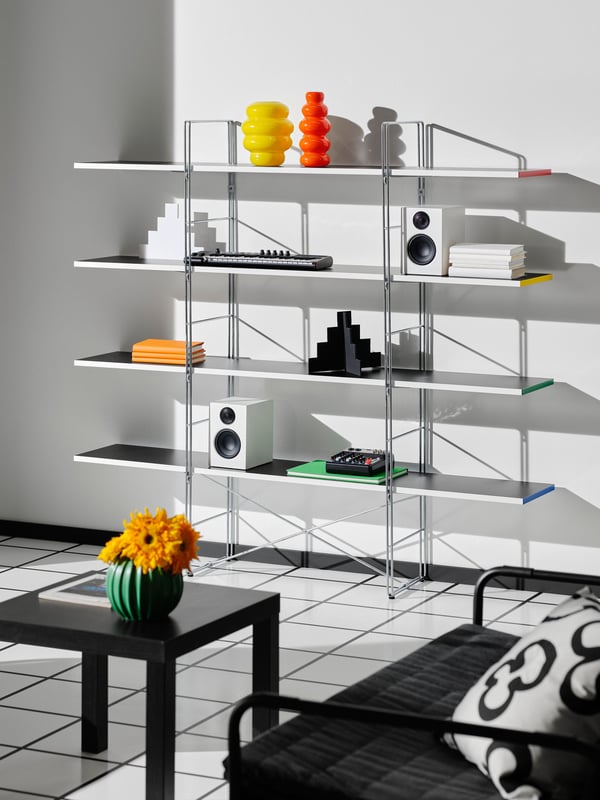 A BYAKORRE open shelving unit is placed against a wall. On the shelves, there are two KÄLLARHALS vases, speakers, and more.