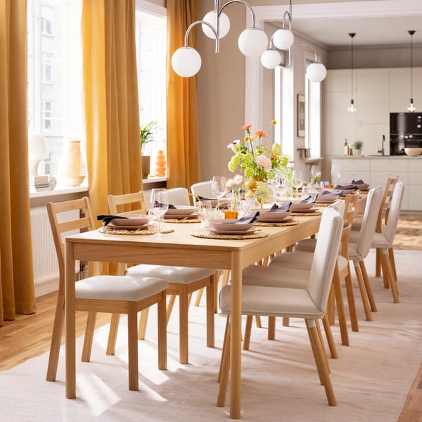 A stylish dining room featuring a TONSTAD table with wooden finish, surrounded by chairs and elegant table settings.