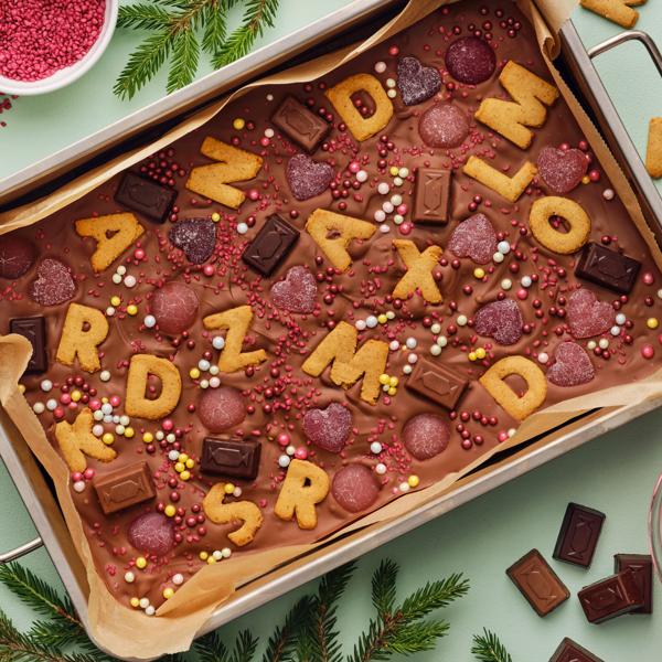 Et brett med smeltet sjokolade, fargerike søtsaker og KAFFEREP bokstavformede kjeks i en morsom og festlig dessert.