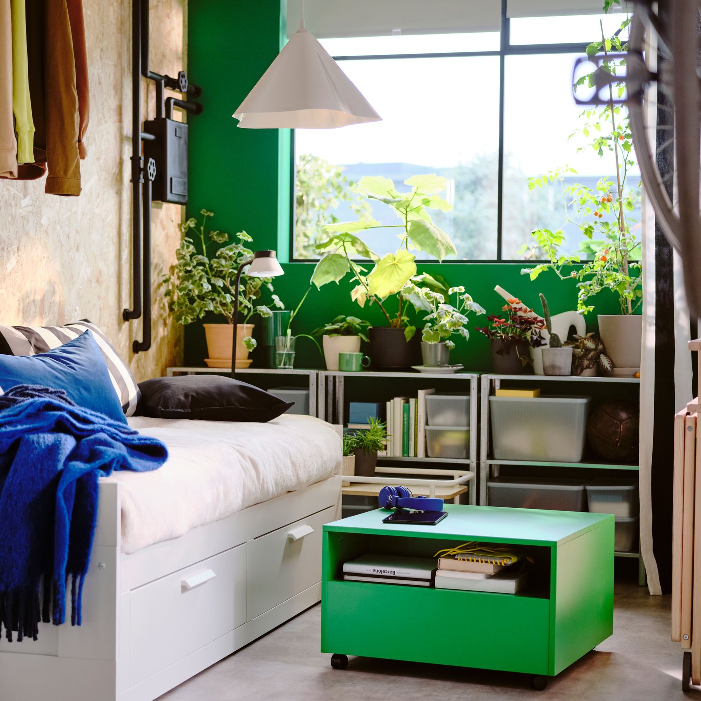 A white BRIMNES day-bed with 2 drawers in a green and white bedroom with a green GARNANÄS coffee table on the floor in front.