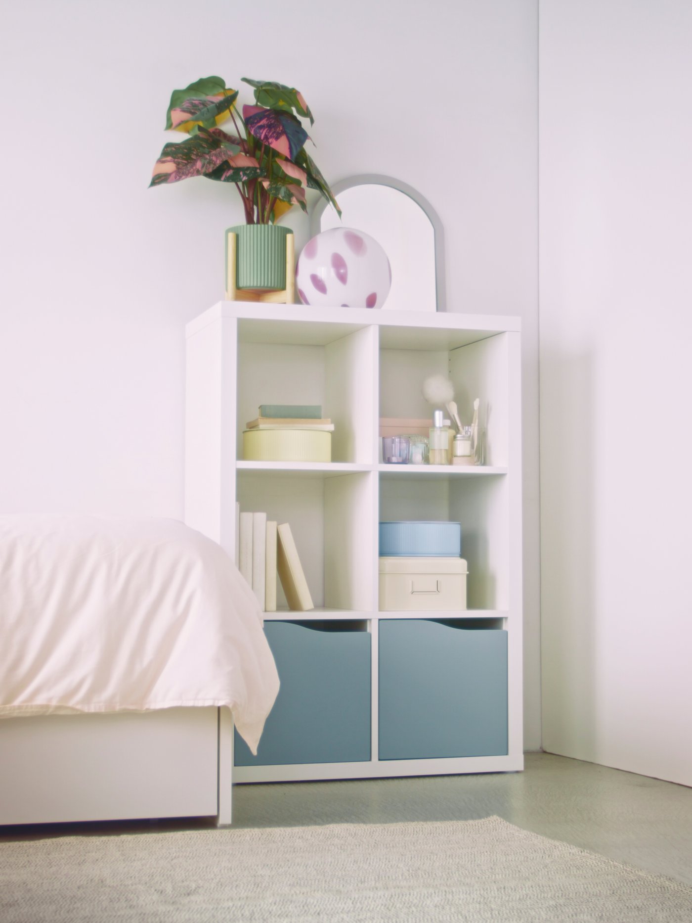 A wave shaped/light grey-blue KALLAX insert with door in the bedroom