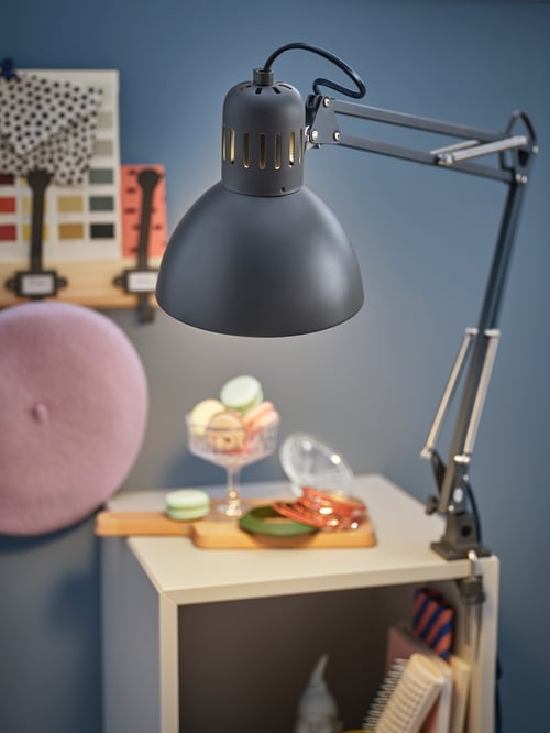 Zogniskowane ujęcie lampy roboczej z szafką z półkami, deską do krojenia, miską z pokrywką i stojakiem z haczykami z tyłu.