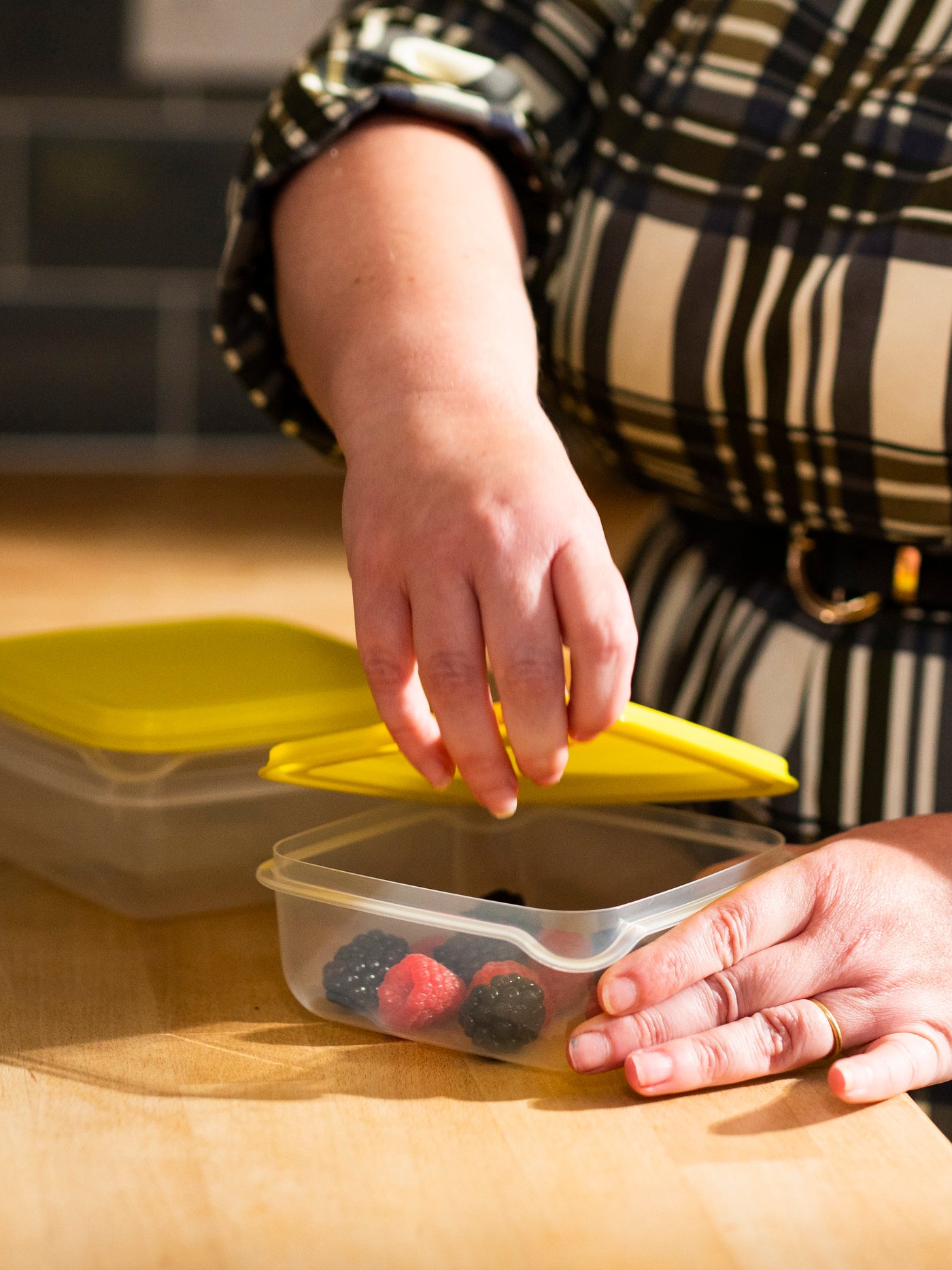 A woman in a kitchen puts the lid on a PRUTA food container.
