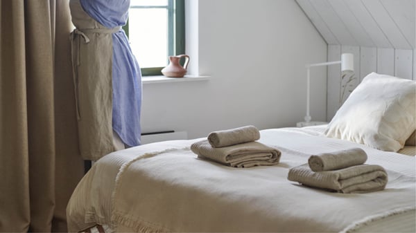 Un plaid ODDRUN de couleur naturelle/beige dans la chambre à coucher