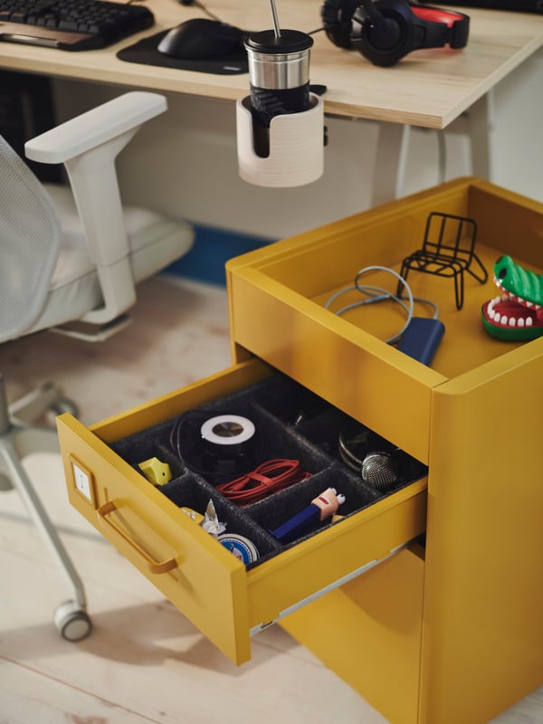 An IKEA IDÅSEN drawer unit on castors beside a gaming desk.