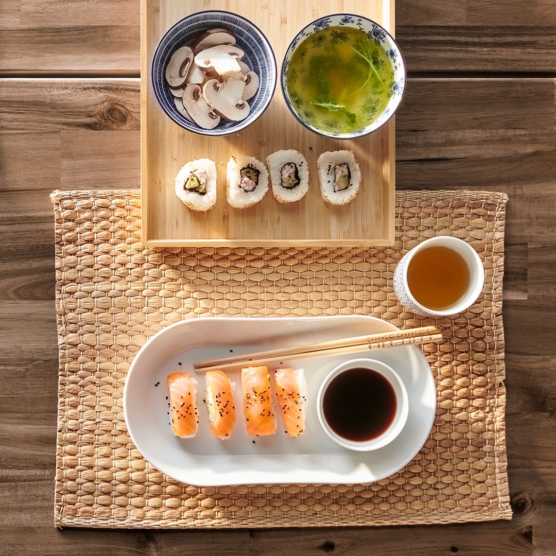Indbydende og flot anrettet sushi set oppefra placeret på et UNDERLAG og en OSTBIT bakke i bambus.
