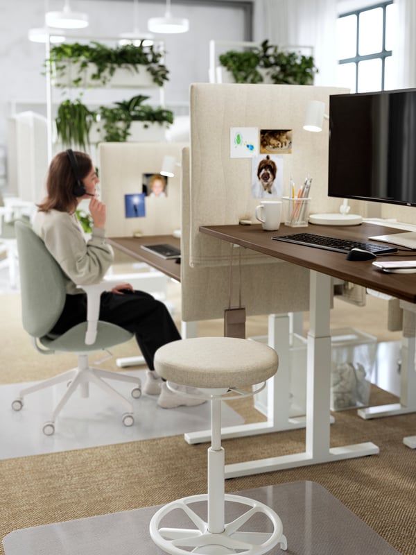 A casual meeting area with four high MITTZON conference tables and four LIDKULLEN sit/stand support. A beige cosy rug.