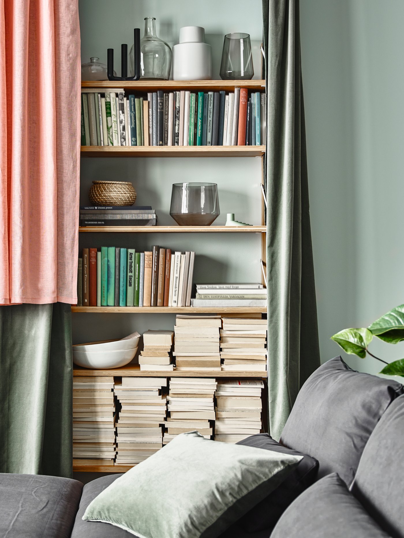 A living room with a full shelf behind LEJONGAP curtains, one pink and two green.