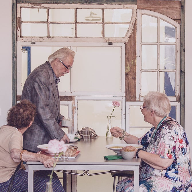 Tři starší lidé sedí u stolu.