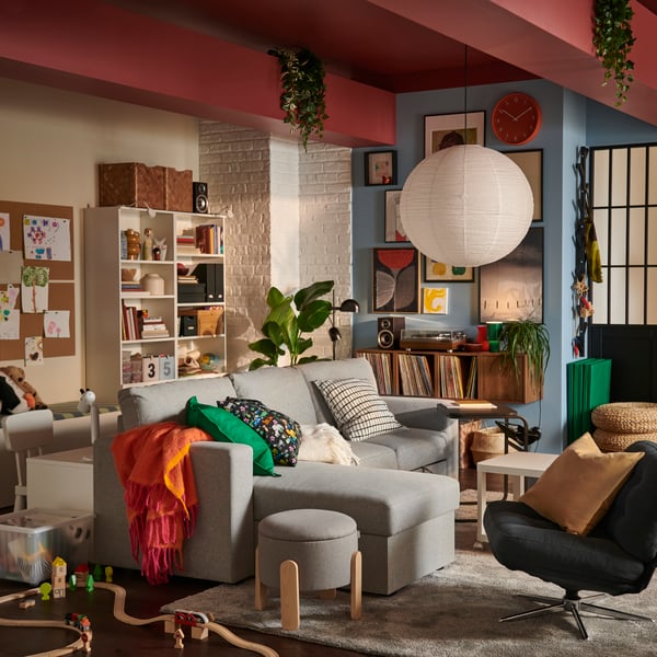 A softly sunlit living room featuring a beige/grey BÅRSLÖV 3-seat sofa-bed with chaise longue, surrounded by playful decor.
