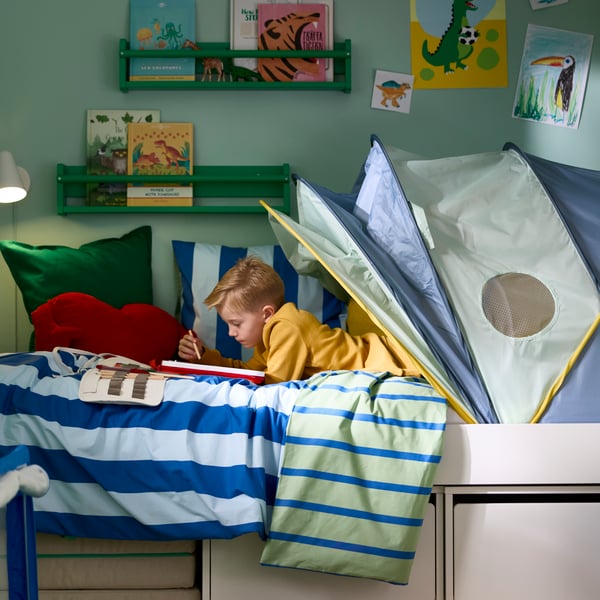 Ein Bettwäscheset aus Bettbezug und Kissenbezug von BARNDRÖM auf einem Kinderbett mit Spielzeug und Wanddekoration in einem farbenfrohen Zimmer.