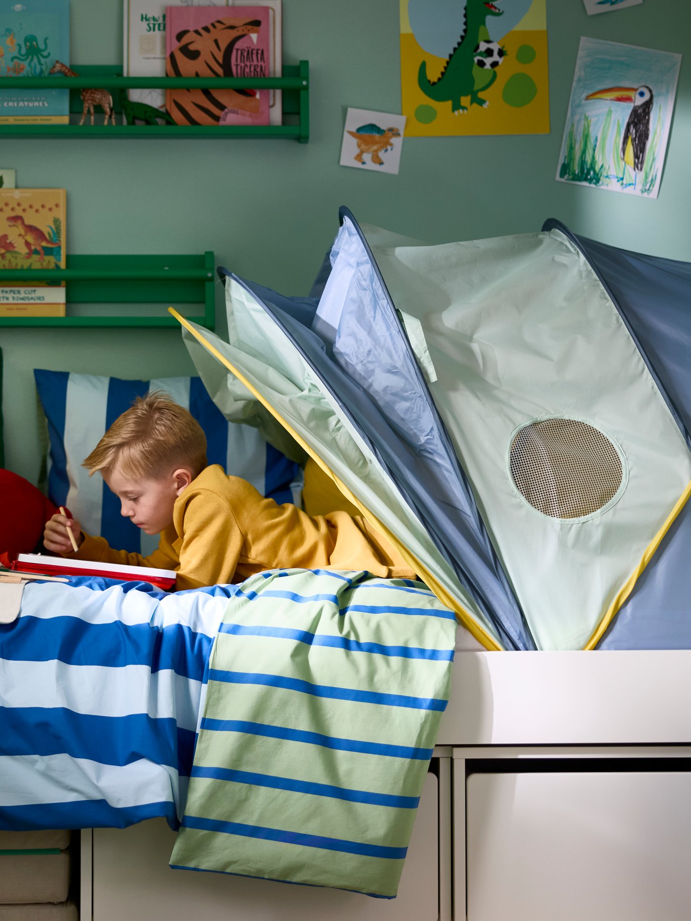 A BARNDRÖM duvet cover and pillowcase set on a children’s bed with toys and wall art in a colourful room.