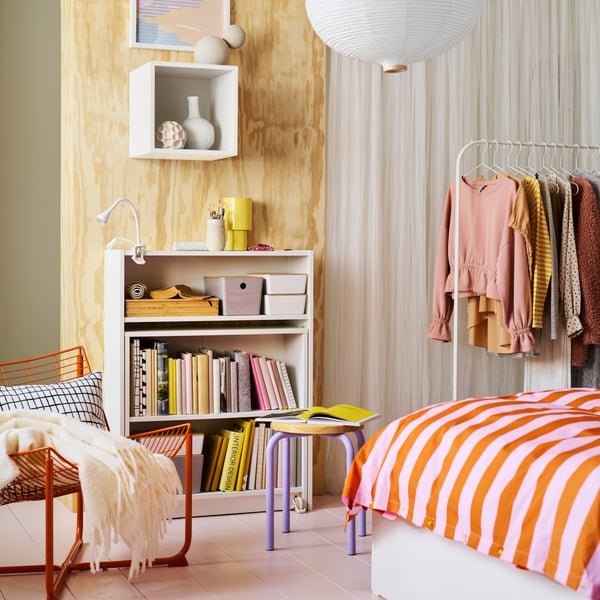 A white BILLY shelving unit with a fold-down table against a light wooden wall, with a NÄVLINGE LED clamp spotlight on the top shelf.