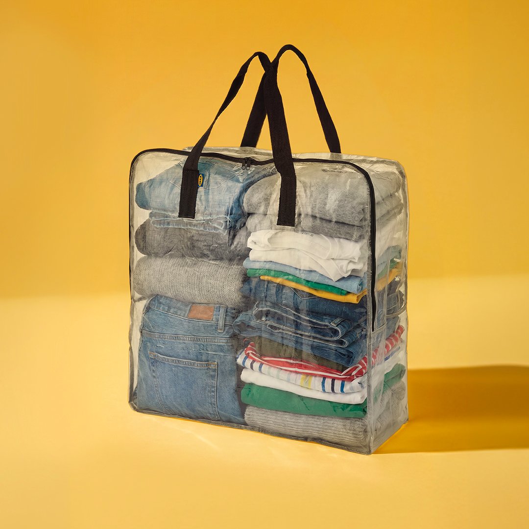 Sac de rangement DIMPA transparent rempli de vêtements biens pliés, sur fond jaune