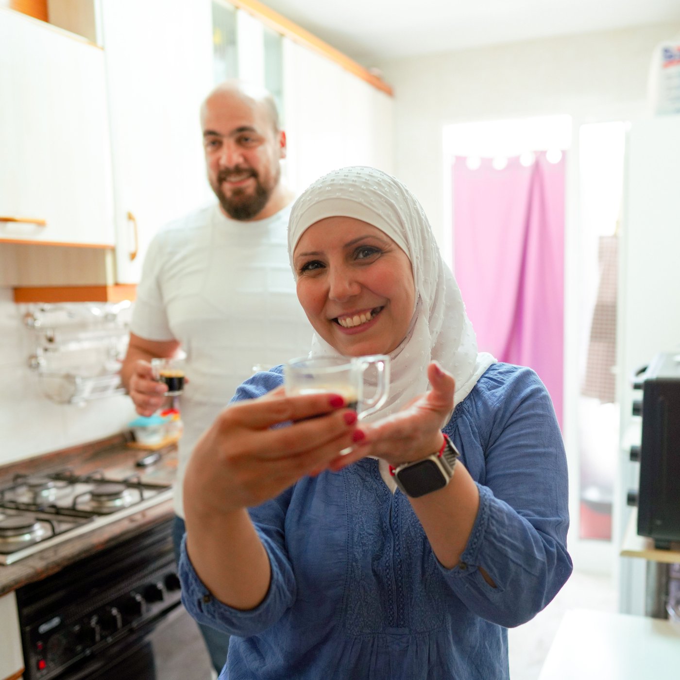 Image of a man and a woman laughing together holding up glasses with coffee. 