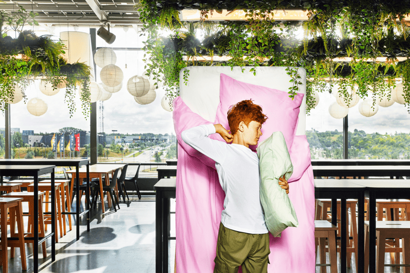 Nuori henkilö heräämässä sängystä IKEA-ravintolassa. Valmiina aamupalalle!